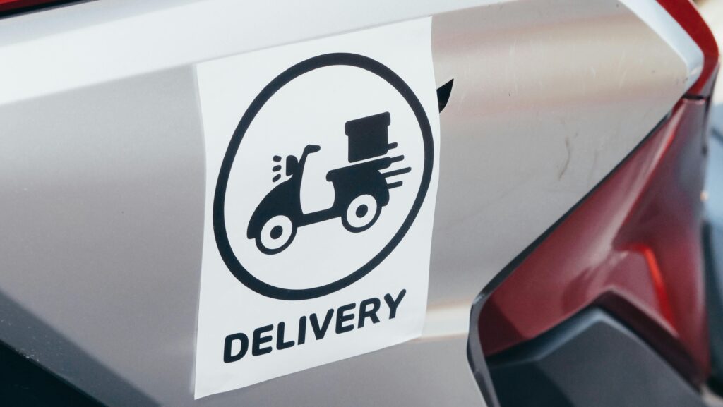 pexels photo 6867964 6867964 A delivery sticker featuring a scooter on a motorcycle's metallic surface.