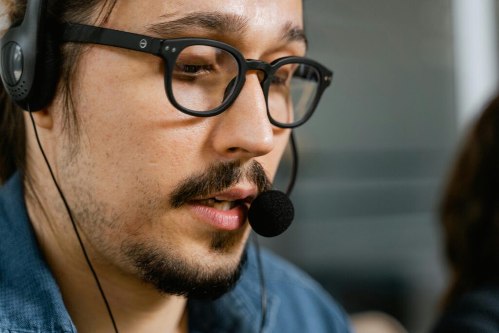pexels photo 7709193 7709193 Close-up of a call center agent with a headset and eyeglasses providing customer support.